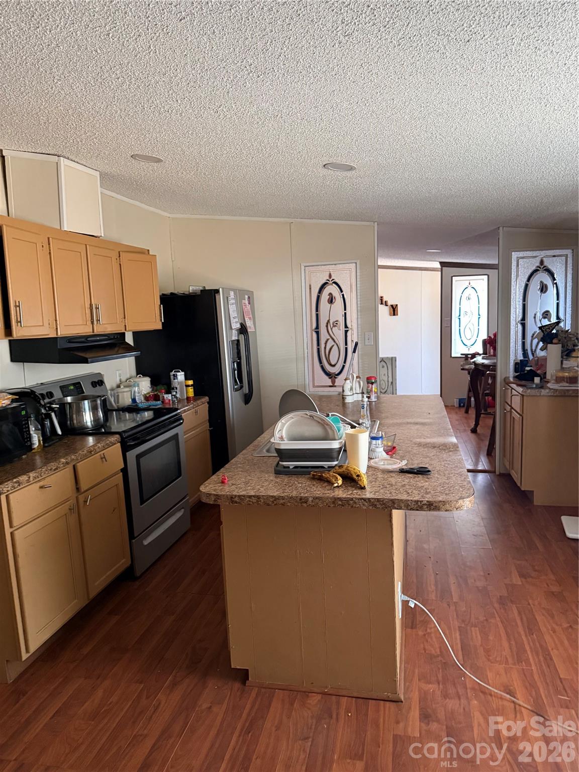 232 Fern Hill Road Troutman, NC 28166 - Photo 8 of 12 a kitchen with kitchen island granite countertop a stove top oven a sink dishwasher and white cabinets with wooden floor