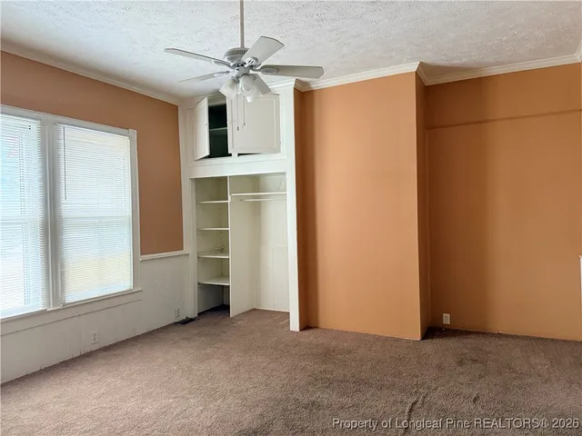 an empty room with windows and ceiling fan
