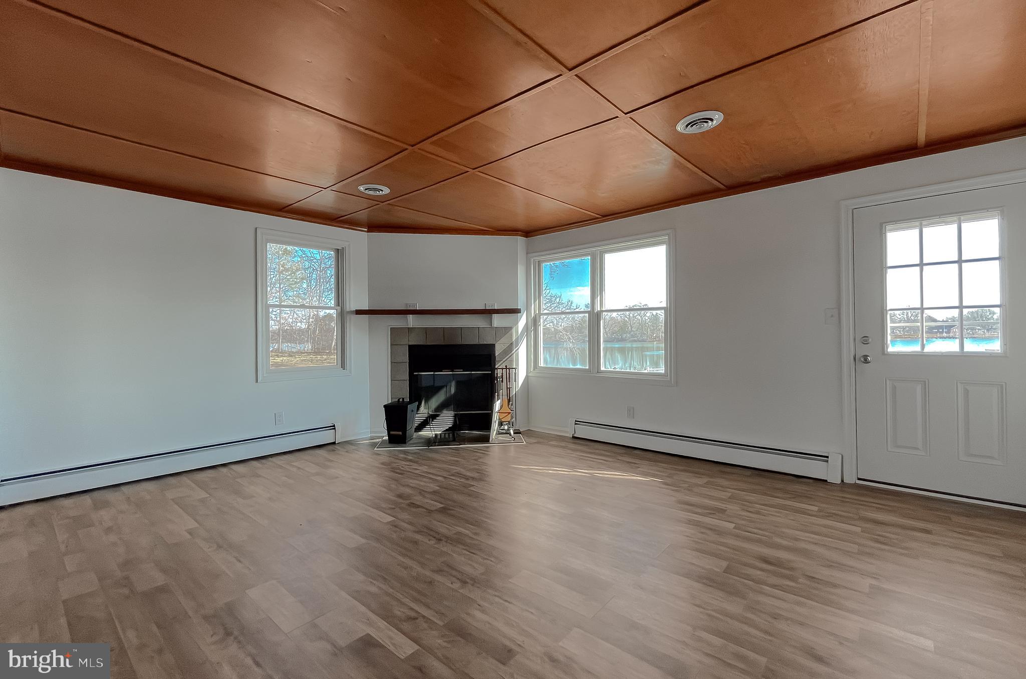 37117 Moore Road Bushwood, MD 20618 - Photo 11 of 45 an empty room with wooden floor fireplace and windows