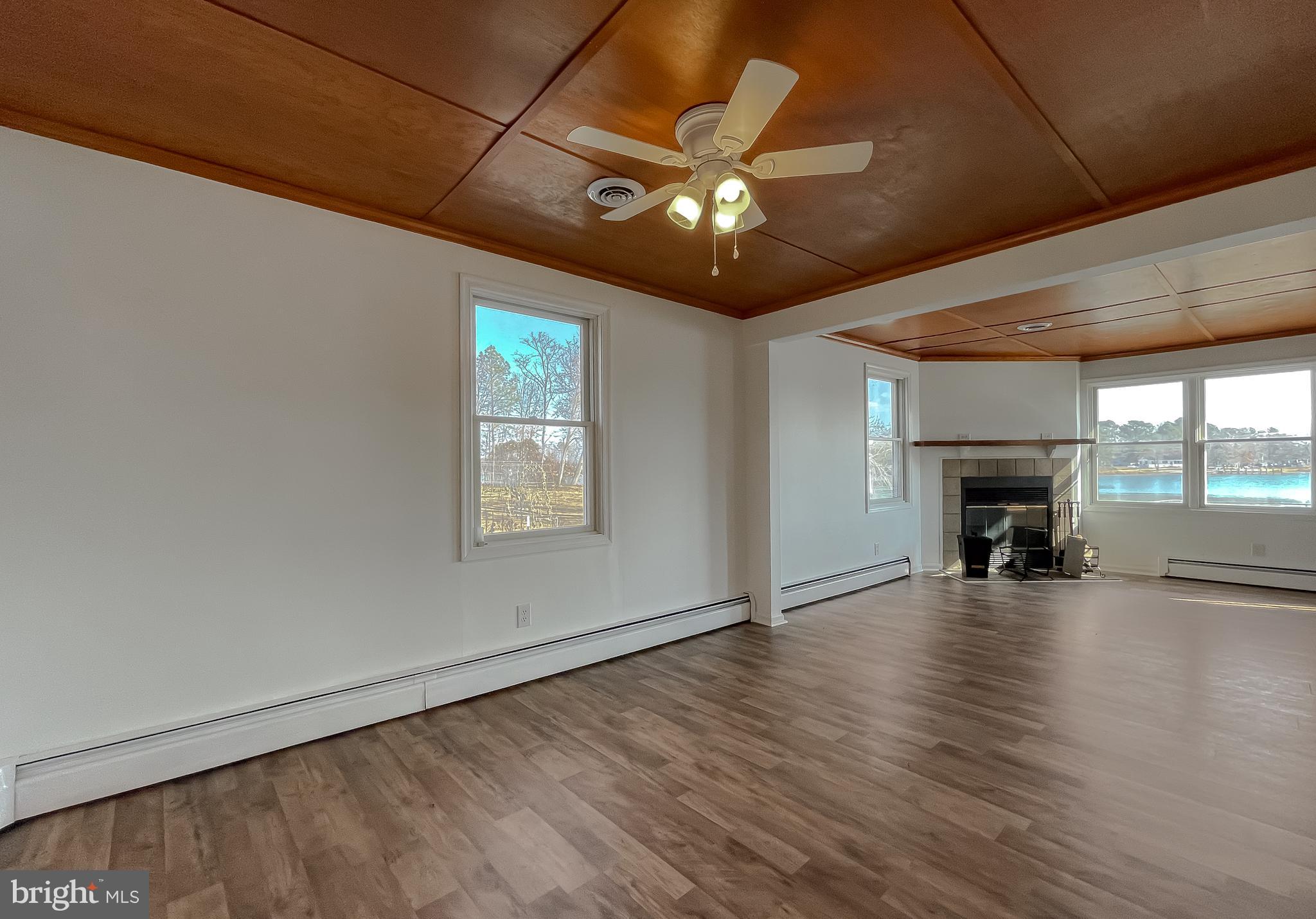 37117 Moore Road Bushwood, MD 20618 - Photo 17 of 45 an empty room with wooden floor fireplace and chandelier