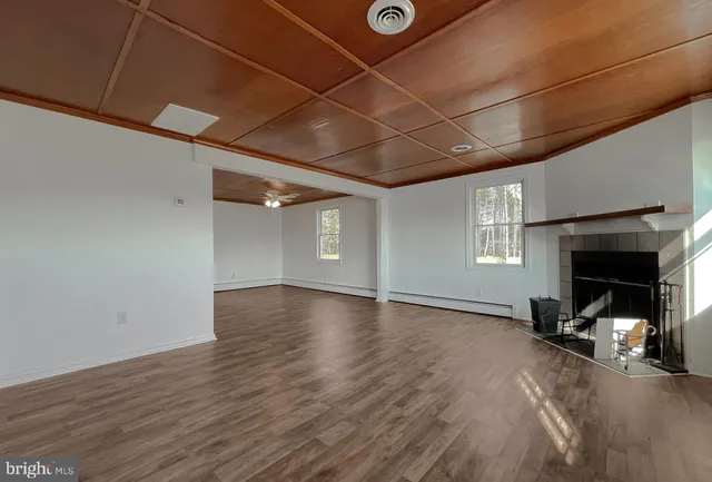an empty room with wooden floor fireplace and windows