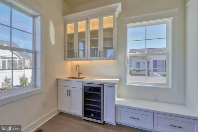 a view of kitchen with stainless steel appliances granite countertop a stove top oven a refrigerator and white cabinets with wooden floor
