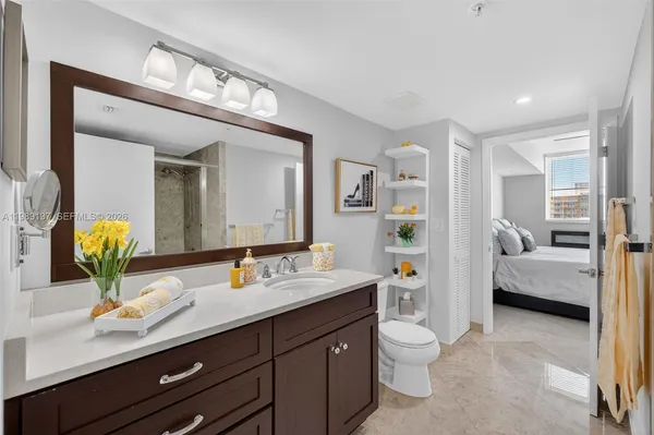 a en suite bathroom with a granite countertop sink and a mirror with toilet
