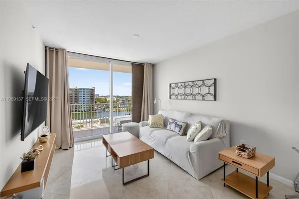 a living room with furniture a flat screen tv and a floor to ceiling window