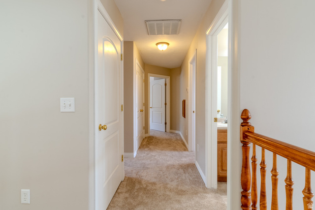 598 Hollow Creek Road Draper, UT 84020 - Photo 74 of 110 Carpeted hallway featuring light neutral wall paint, white trim, and a classic wood banister