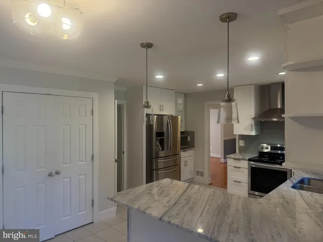 a kitchen with stainless steel appliances kitchen island granite countertop a refrigerator and a sink