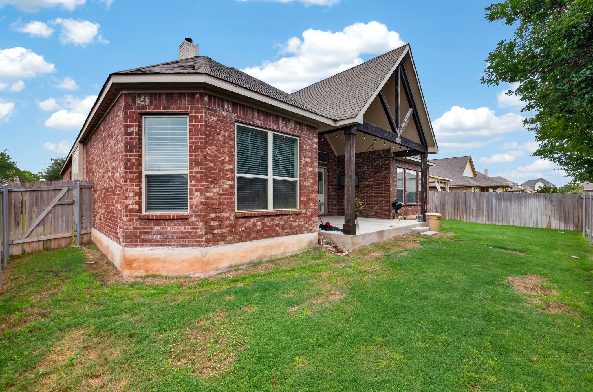 1017 Tabernash Leander, TX 78641 - Photo 36 of 38 Expansive backyard featuring a covered patio with exposed wood beams, brick exterior, and a privacy fence