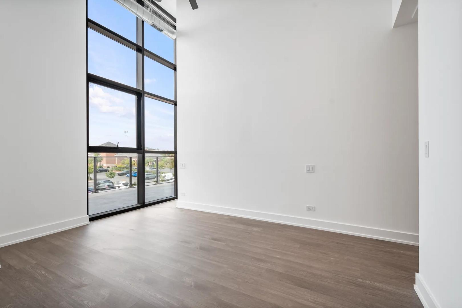 728 Waukegan Road, Unit 206 Deerfield, IL 60015 - Photo 12 of 18 a view of an empty room with wooden floor and windows