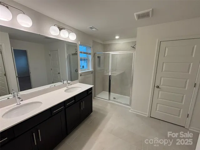 a bathroom with a double vanity sink mirror and shower