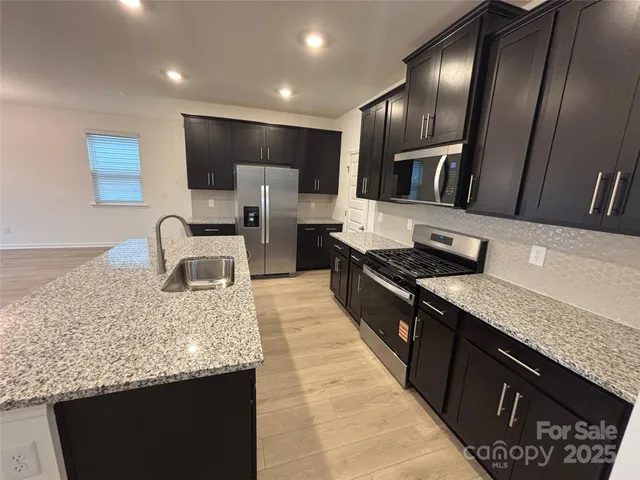 a kitchen with stainless steel appliances granite countertop a sink stove and refrigerator