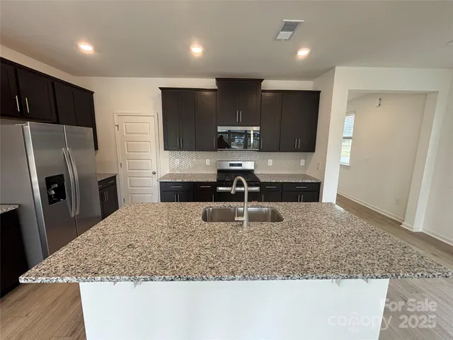 a kitchen with stainless steel appliances granite countertop a sink refrigerator and microwave