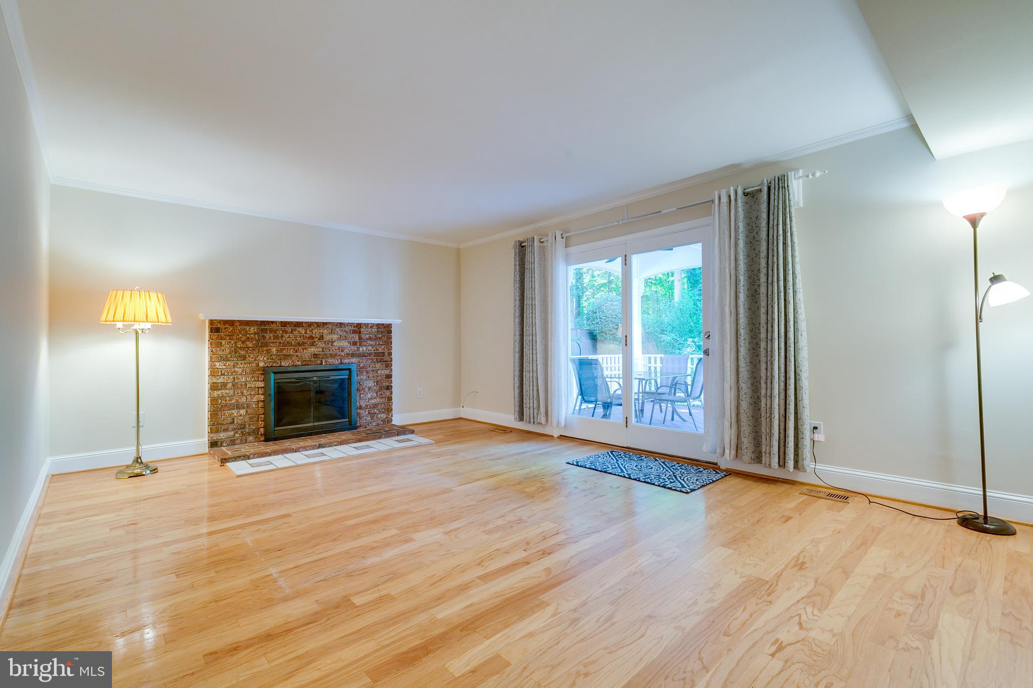 7007 Barnacle Place Burke, VA 22015 - Photo 11 of 49 a view of an empty room with wooden floor fireplace and a window