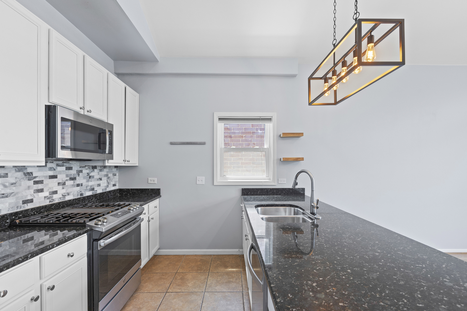 1267 North Honore Street, Unit 3 Chicago, IL 60622 - Photo 4 of 17 a kitchen with granite countertop a stove top oven microwave and cabinets