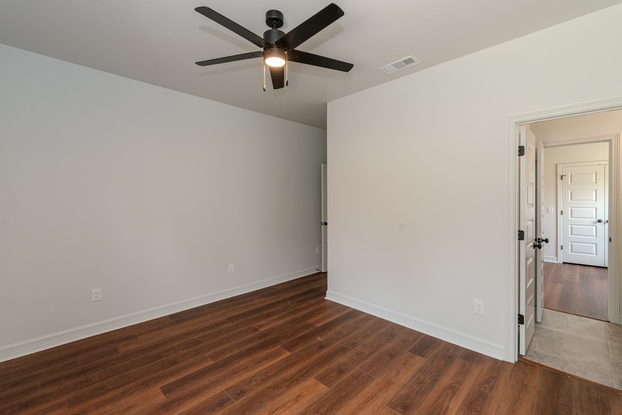 7820 Tolivar Road Beaumont, TX 77713 - Photo 22 of 47 an empty room with wooden floor and a ceiling fan