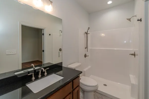 a bathroom with a sink a toilet a mirror and shower