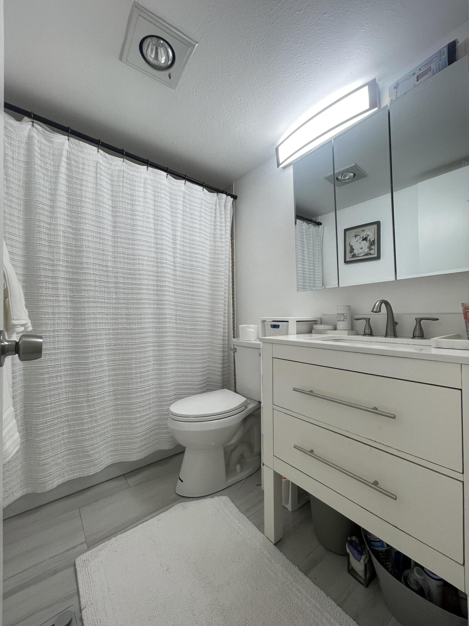 49 Mansfield B Boca Raton, FL 33434 - Photo 28 of 31 a bathroom with a toilet a sink and mirror