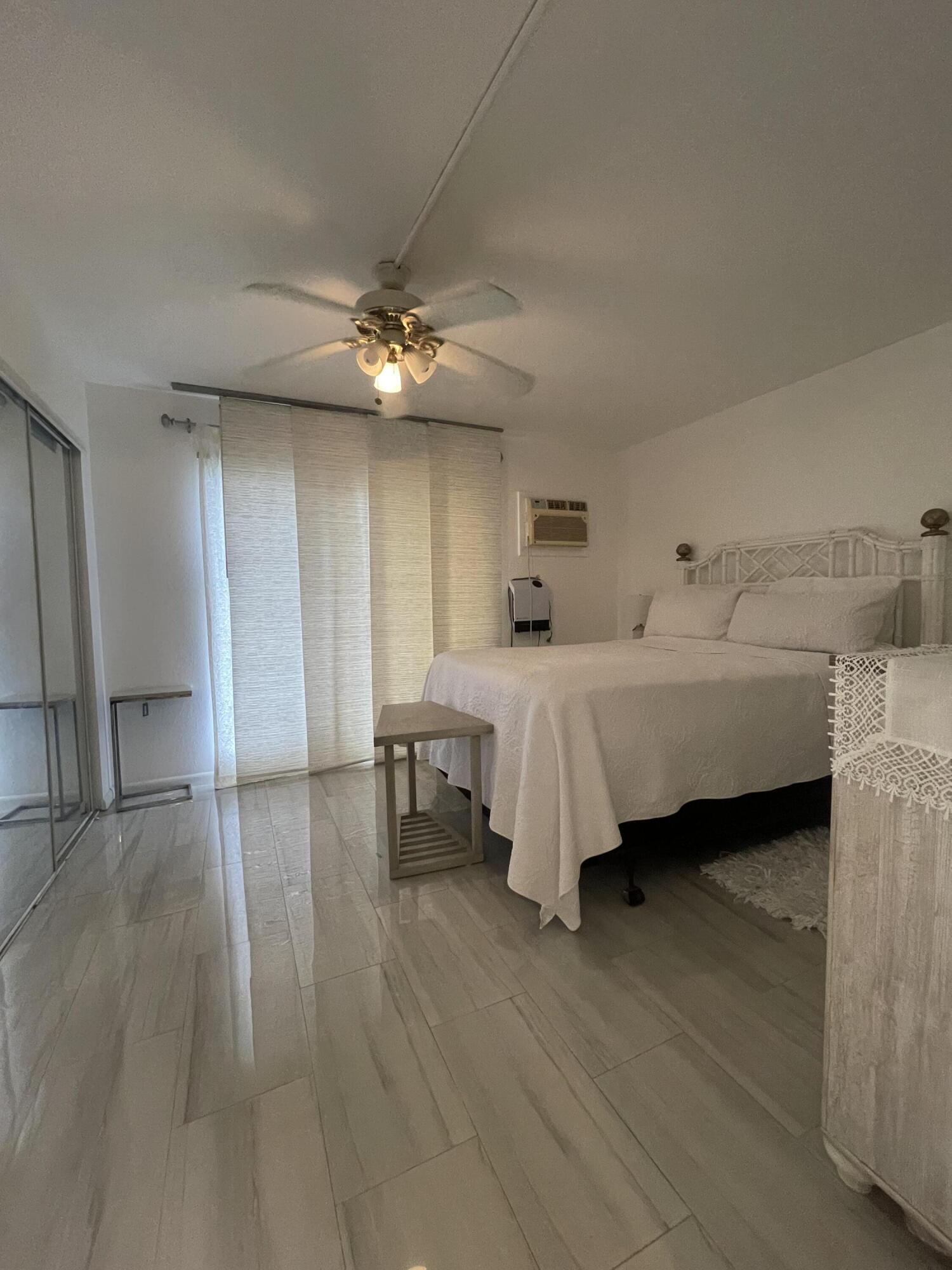 49 Mansfield B Boca Raton, FL 33434 - Photo 30 of 31 a bedroom with a bed and a chandelier