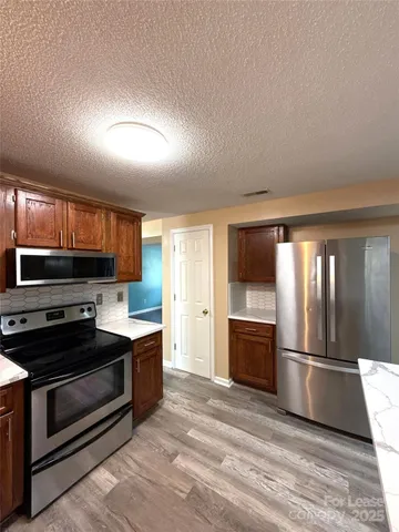 a kitchen with stainless steel appliances granite countertop a refrigerator and a stove top oven