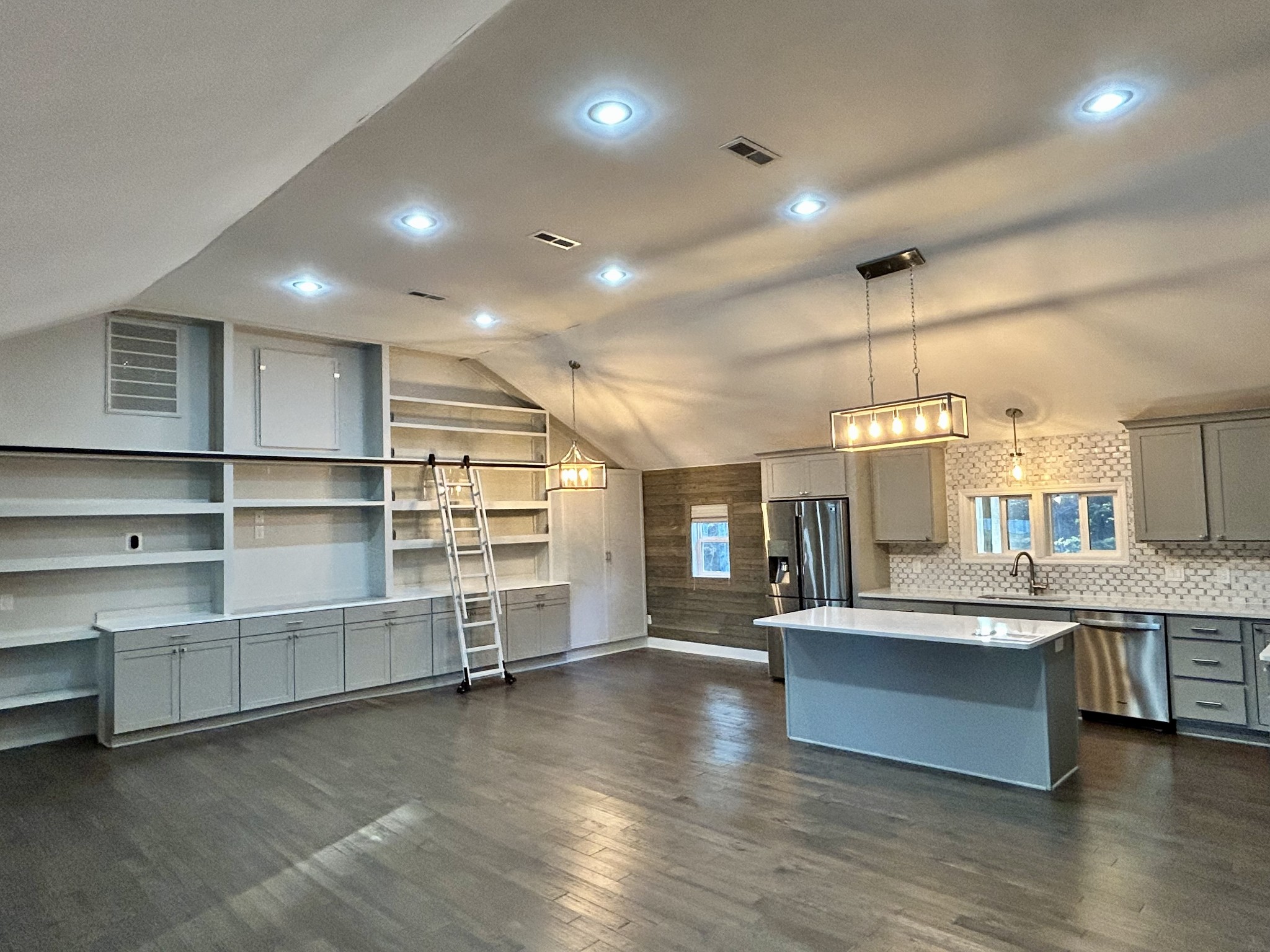 a large kitchen with stainless steel appliances a large counter top a stove and a wooden floors