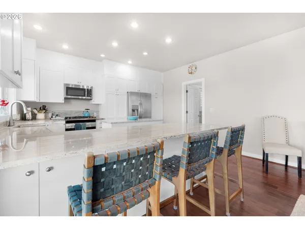 a kitchen with stainless steel appliances granite countertop a stove top oven a sink a dining table and chairs