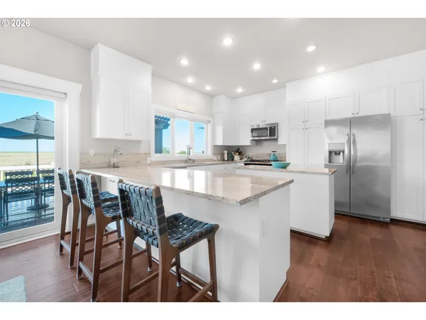 a kitchen with stainless steel appliances granite countertop a table chairs sink refrigerator and cabinets