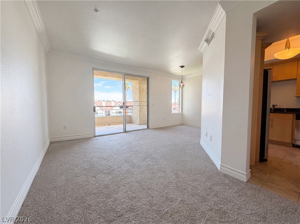 230 East Flamingo Road, Unit 320 Las Vegas, NV 89169 - Photo 8 of 19 A spacious, naturally illuminated room features carpet flooring and crown molding, opening to a private balcony.