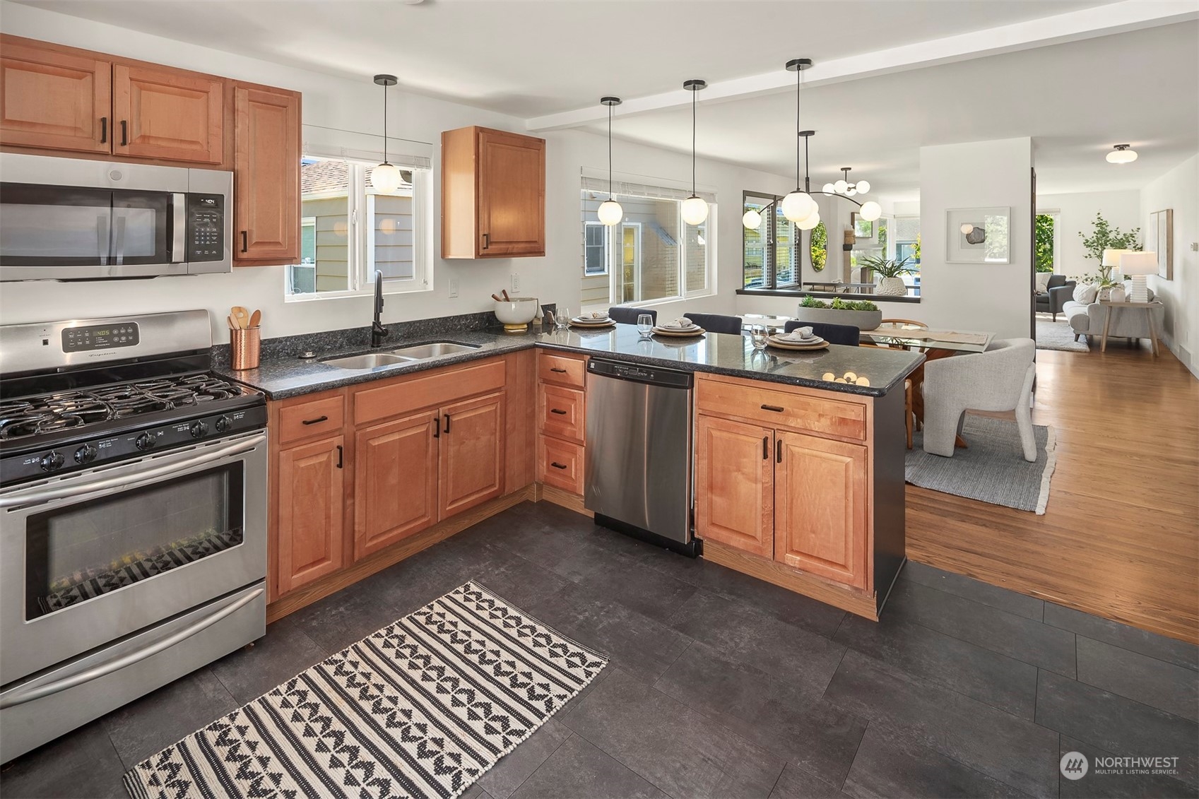 3226 60th Avenue Southwest Seattle, WA 98116 - Photo 8 of 34 a large kitchen with stainless steel appliances kitchen island granite countertop a stove a sink and a microwave