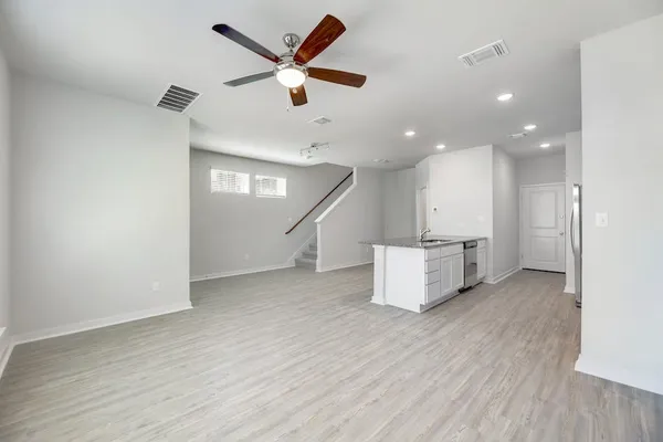 an empty room with wooden floor and a ceiling fan