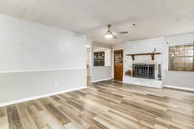 an empty room with windows and fireplace