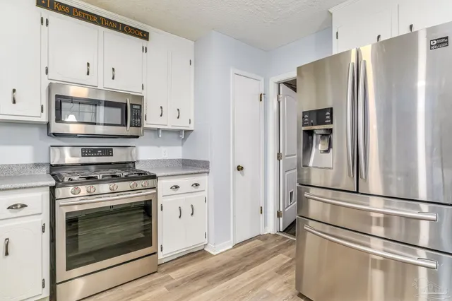 a kitchen with stainless steel appliances white cabinets and wooden floor