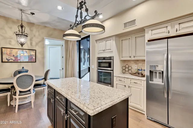 a kitchen with granite countertop a table chairs stainless steel appliances and cabinets
