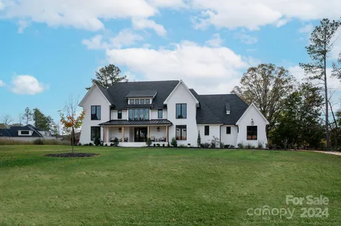 a view of a house with a big yard and large trees