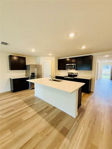 a large kitchen with stainless steel appliances kitchen island a large counter top a stove and a wooden floors
