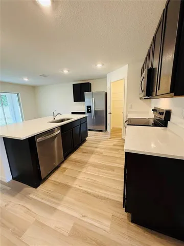 a large kitchen with stainless steel appliances kitchen island granite countertop a sink and a microwave