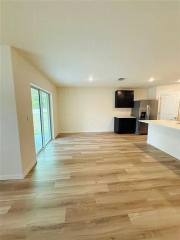 a view of kitchen and empty room with wooden floor