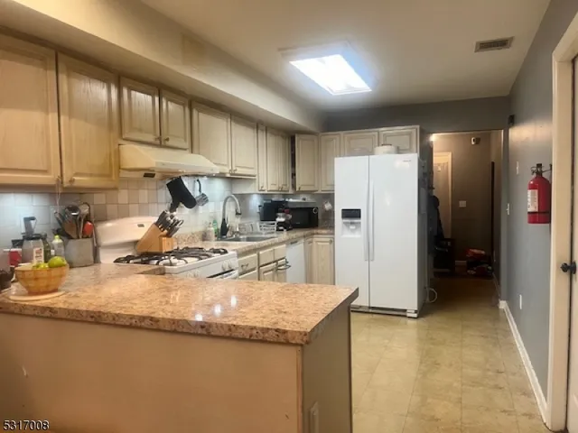 a kitchen with a refrigerator a sink a stove a microwave and wooden cabinets