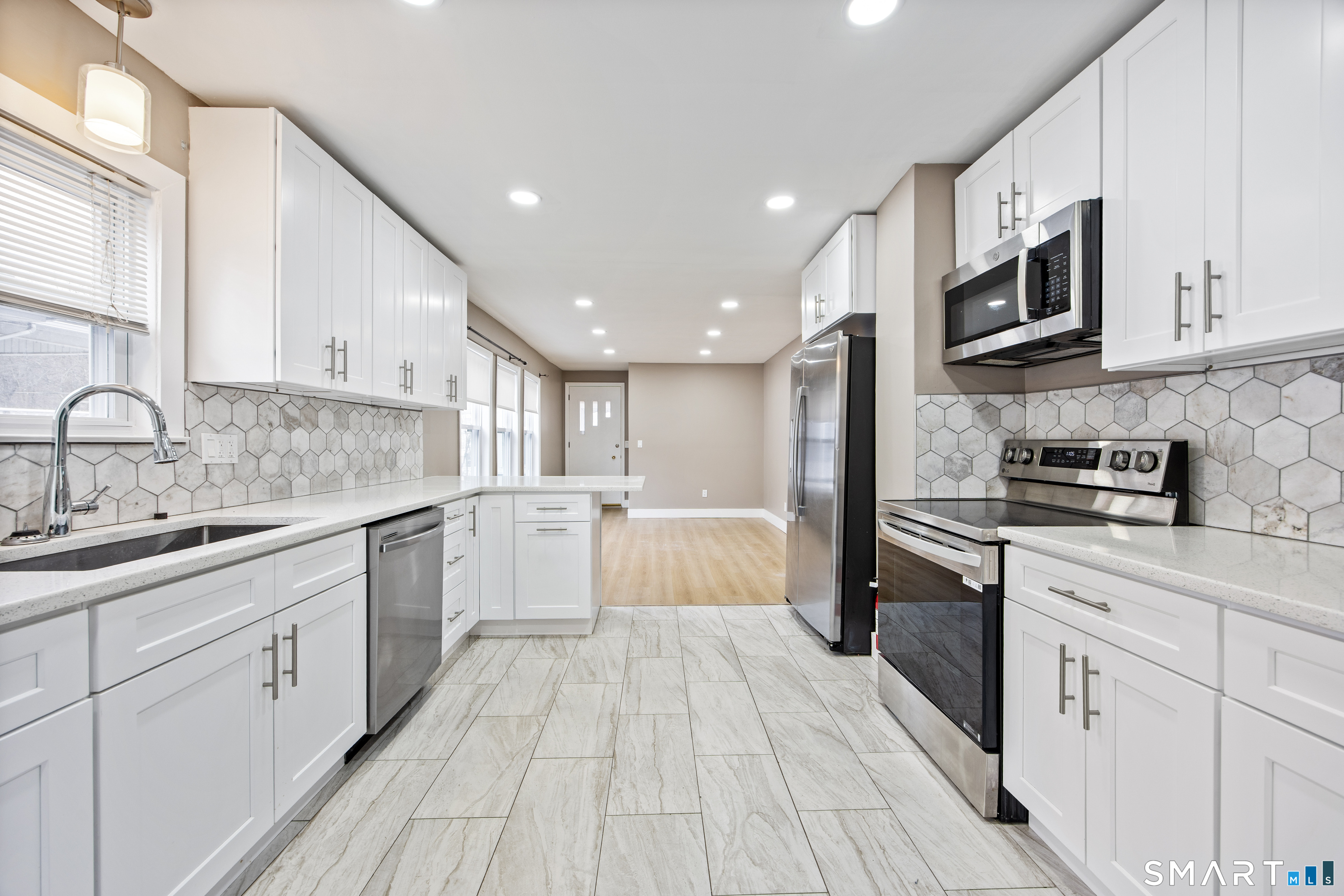 a large kitchen with stainless steel appliances granite countertop a large stove a sink dishwasher and a refrigerator with wooden floor