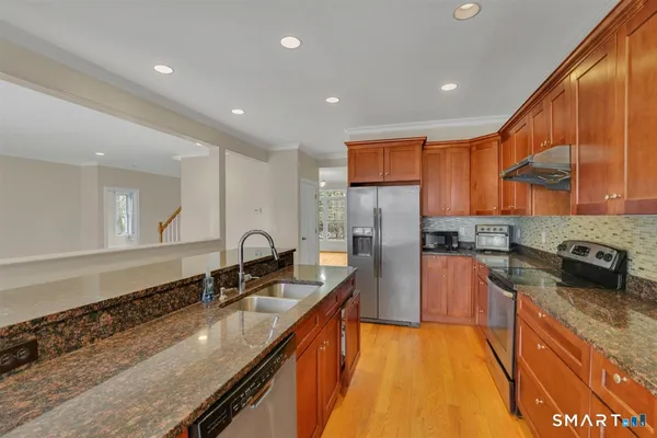 a large kitchen with stainless steel appliances granite countertop a sink a stove and a refrigerator
