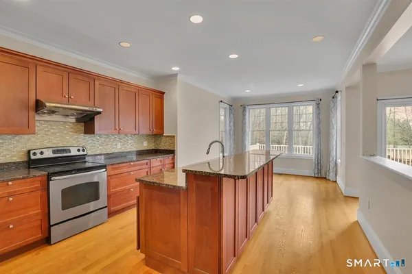 a kitchen with stainless steel appliances granite countertop a stove a sink dishwasher and a refrigerator with wooden floor