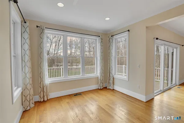 a view of an empty room with a window and wooden floor