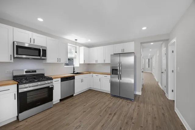 a kitchen with stainless steel appliances granite countertop a refrigerator a stove top oven a sink dishwasher and wooden floor