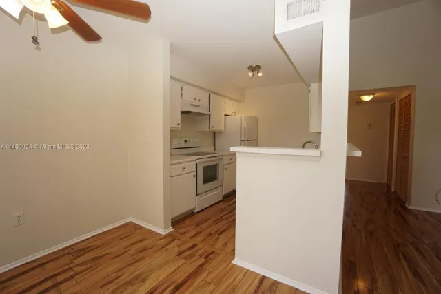 a view of a kitchen with a refrigerator and wooden floor