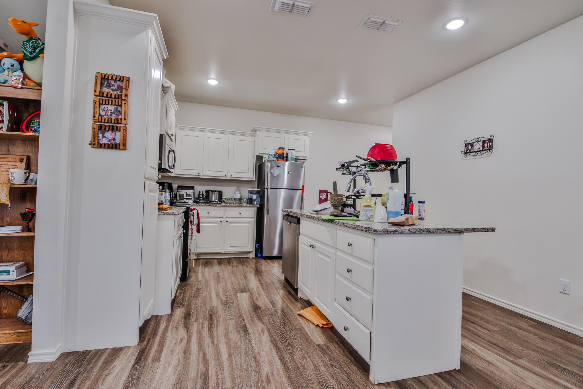 6902 20th Street Lubbock, TX 79407 - Photo 5 of 20 a kitchen with granite countertop white cabinets and wooden floor