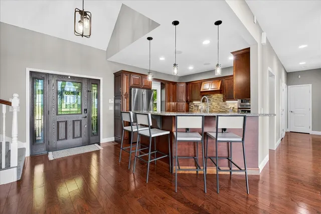 an open kitchen with wooden floor and stainless steel appliances