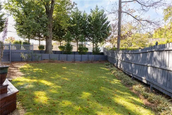 a view of yard with large trees and wooden fence