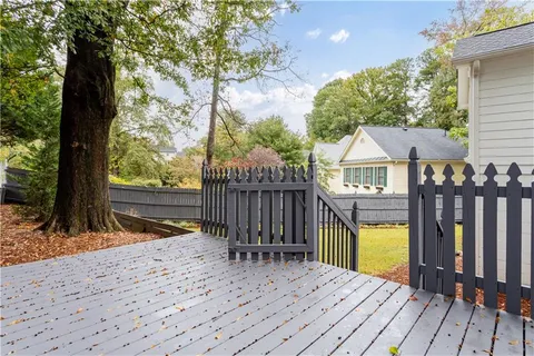 a view of house with wooden deck and a backyard