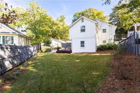 a view of a yard in front of a house with plants and large tree