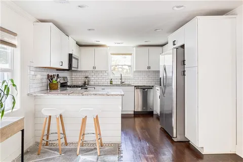 a kitchen with kitchen island granite countertop wooden floors white cabinets and stainless steel appliances