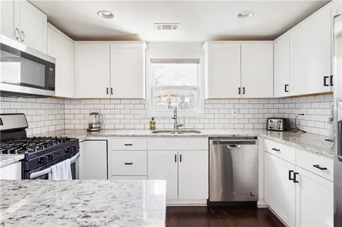 a kitchen with cabinets appliances a sink and a window
