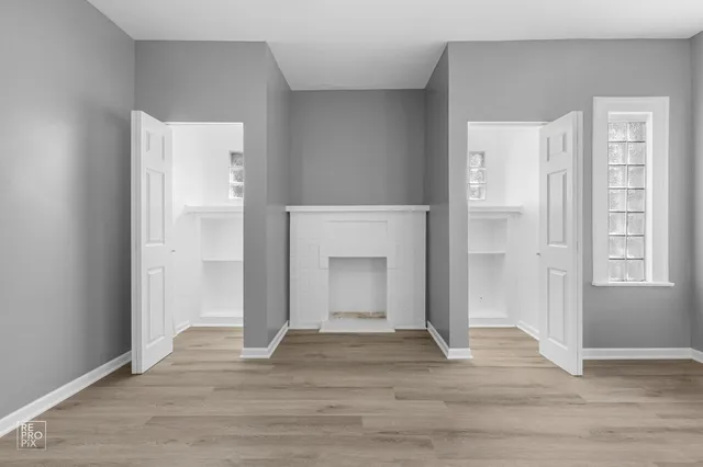 a view of an empty room with wooden floor and a fireplace